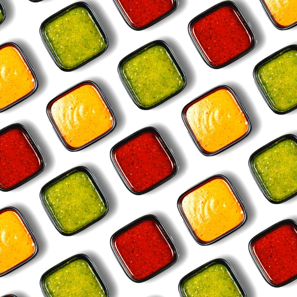 square dishes of sauces on white background