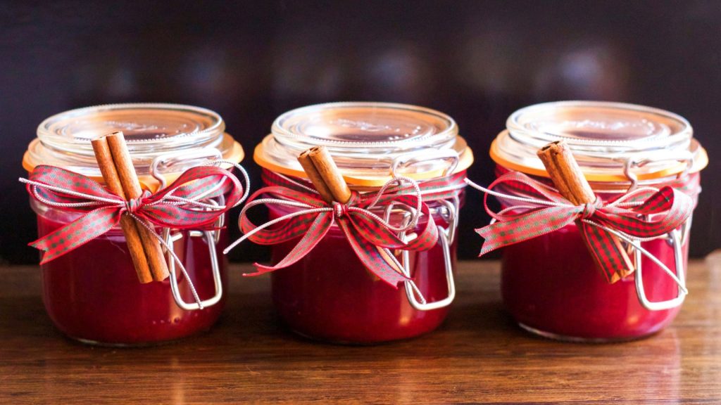 3 canning jars of jam wrapped red and green plaid ribbon and cinnamon sticks