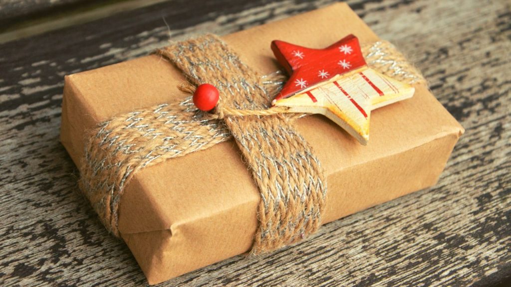 box wrapped in brown paper decorated with a scarf and an ornament