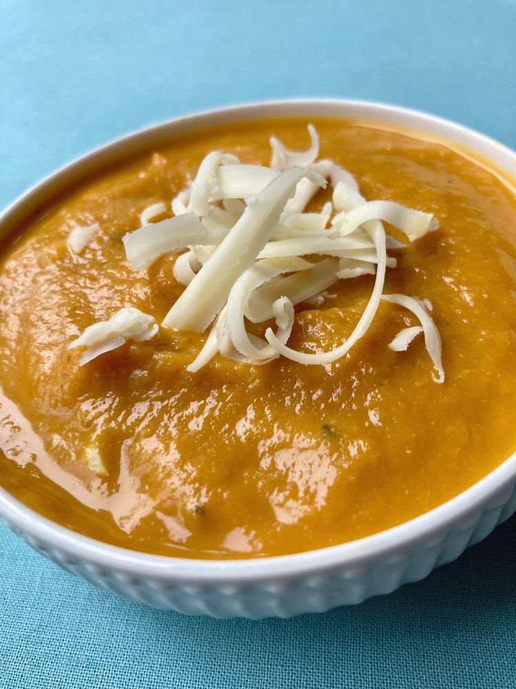bowl of pumpkin chickpea soup topped with shredded cheese