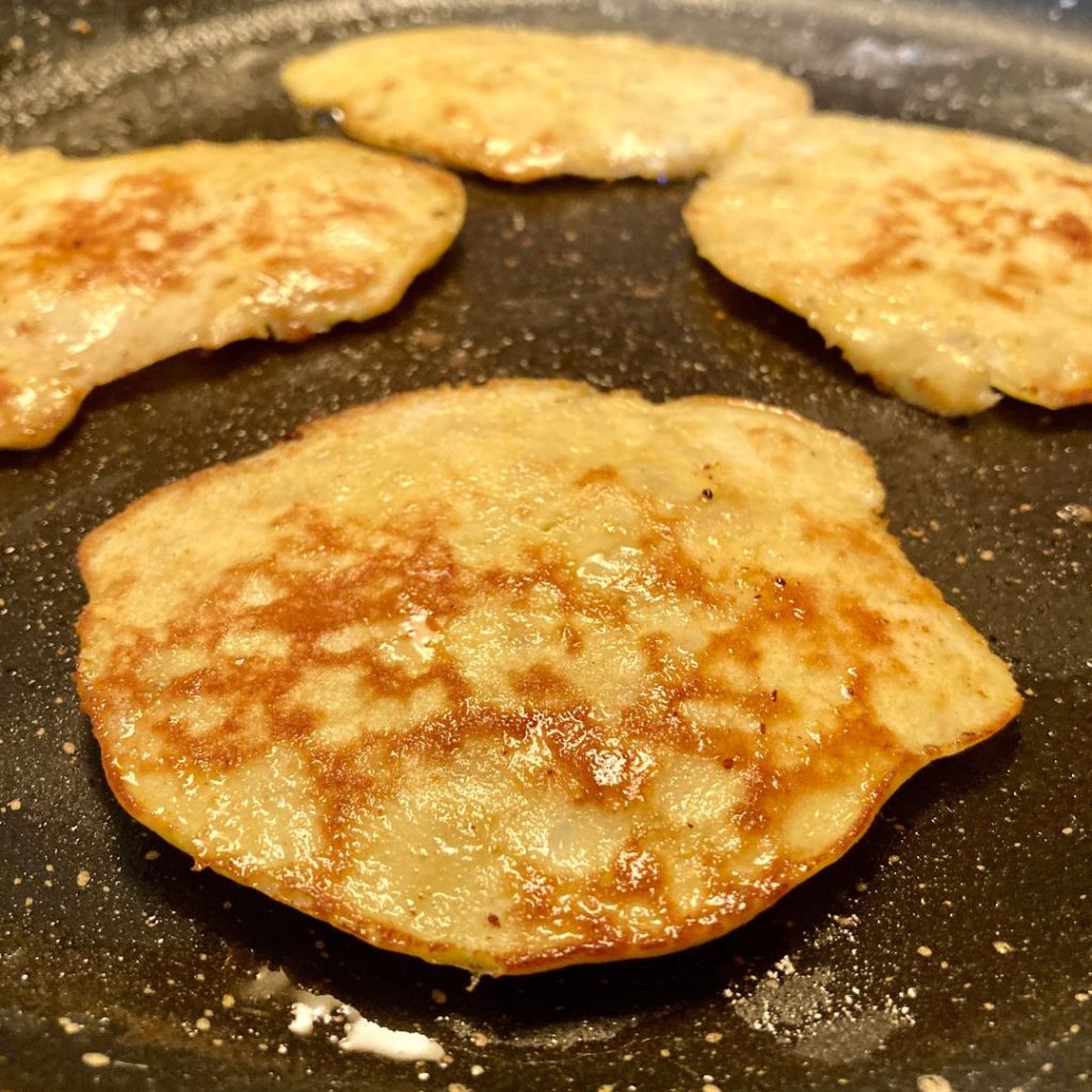 4 silver dollar flourless banana pancakes cooking in a pan