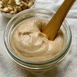 jar of homemade cashew butter with a wooden spreader